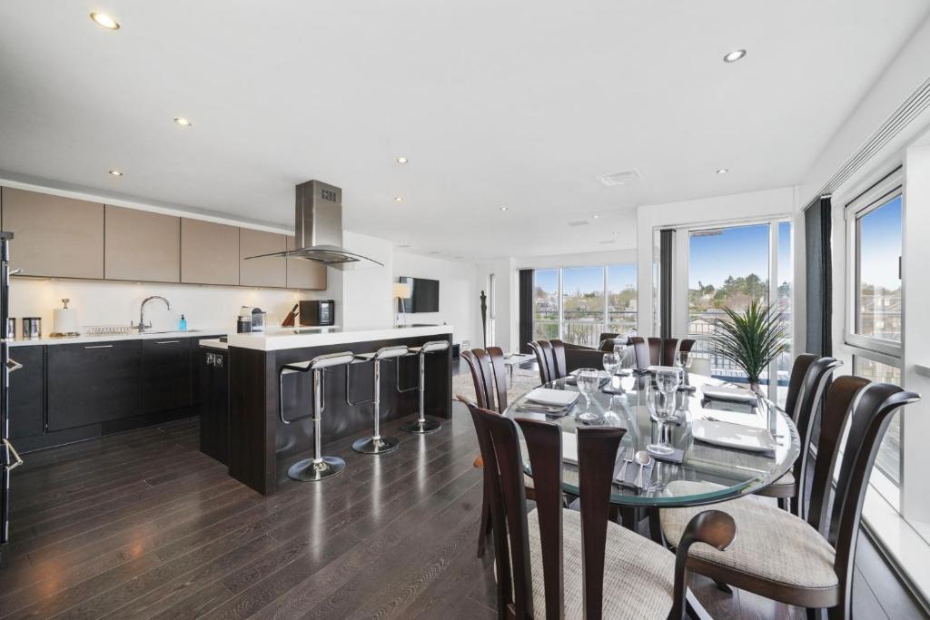 uma cozinha e sala de jantar com uma mesa de vidro e cadeiras em The Penthouse - By Howburn Residence em Aberdeen