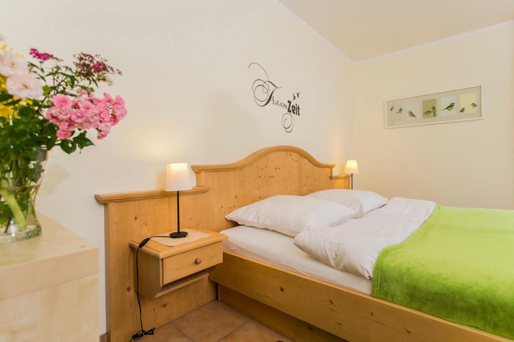 Un dormitorio con una cama y un jarrón de flores. en Landhaus Teuteberg, en Bad Bevensen