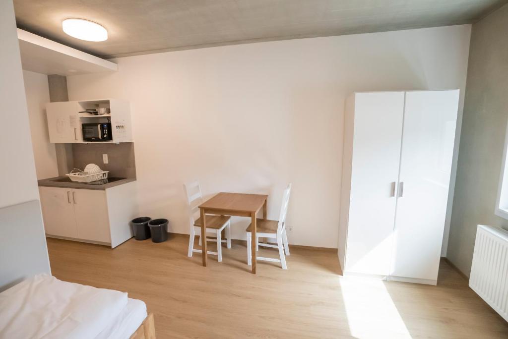 une chambre avec une table et des chaises ainsi qu'une cuisine dans l'établissement SITE.INN Denkendorf, à Denkendorf