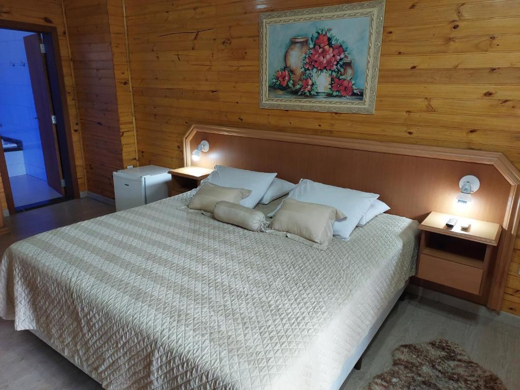 1 dormitorio con 1 cama grande y 2 mesas en Pousada Villa Fiorita, en Canela