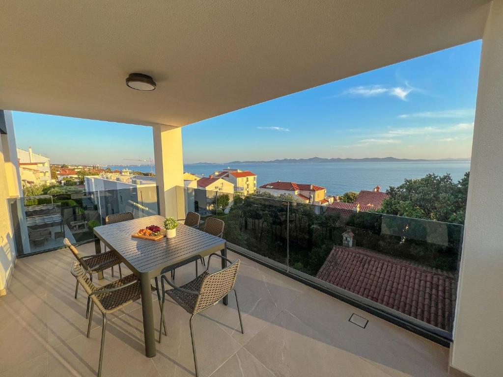 a table and chairs on a balcony with a view of the ocean at Zadar Premium Apartments in Kožino