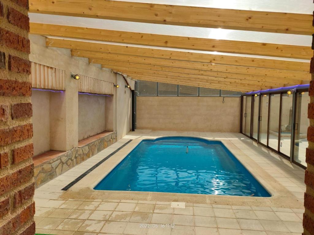Casa Rural Baños del Rey con piscina climatizada في Vega de Santa María: مسبح داخلي بسقف خشبي