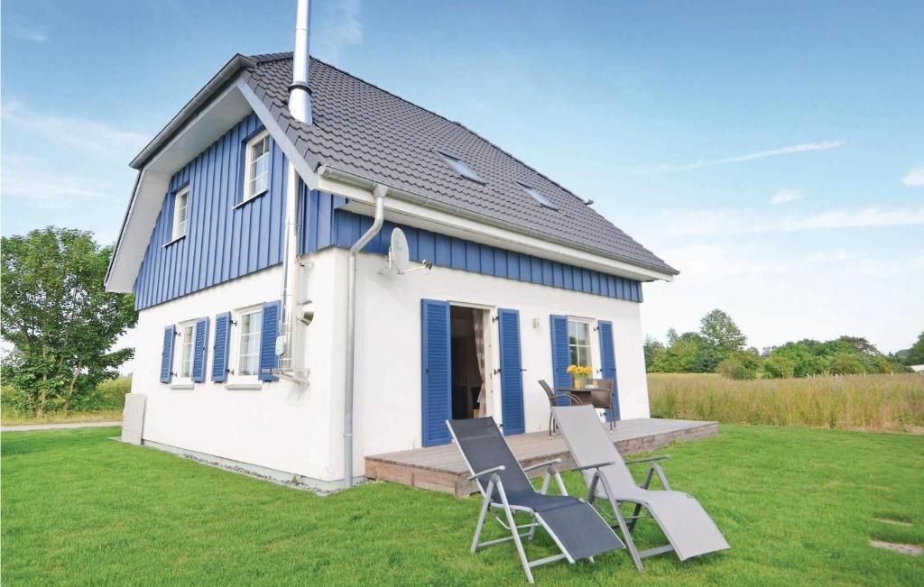 una casa azul y blanca con 2 sillas en el patio en Ferienhaus 18 Altefhr en Altefähr