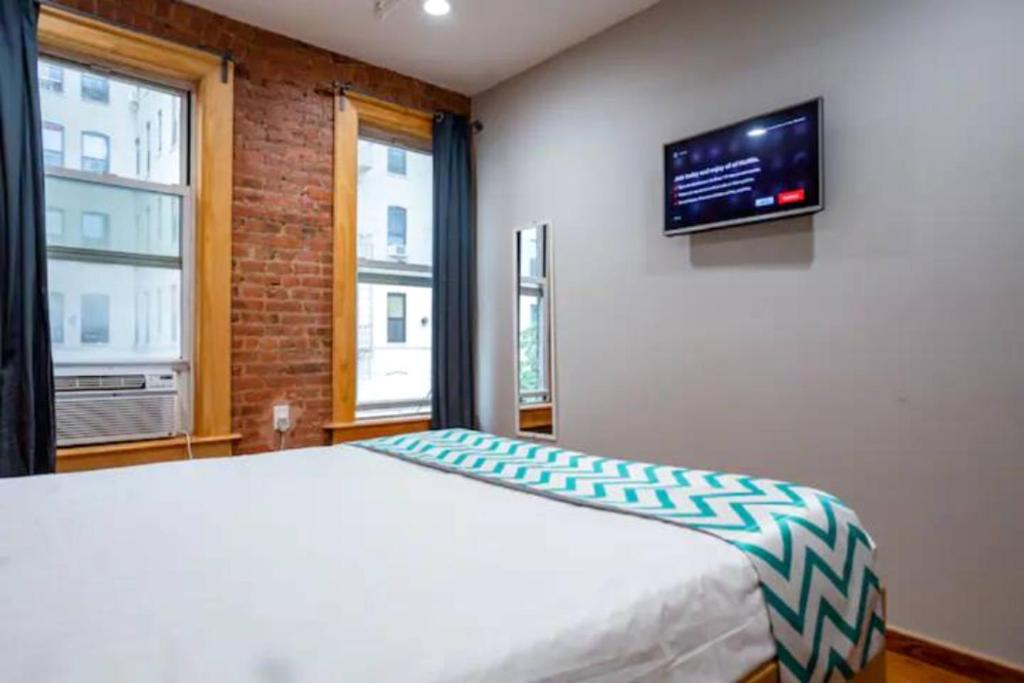 a bedroom with a bed and a tv on the wall at Morris Guest House in Bronx