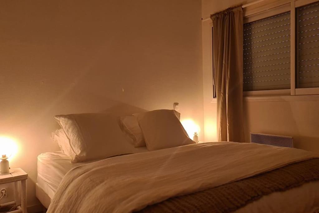 a bedroom with a bed with two pillows and a window at Duplex cosy au centre du Canon, à quelques pas du Bassin in Cap-Ferret