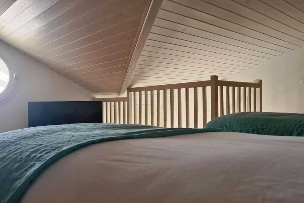 a bed in a bedroom with a wooden ceiling at Duplex cosy au centre du Canon, à quelques pas du Bassin in Cap-Ferret