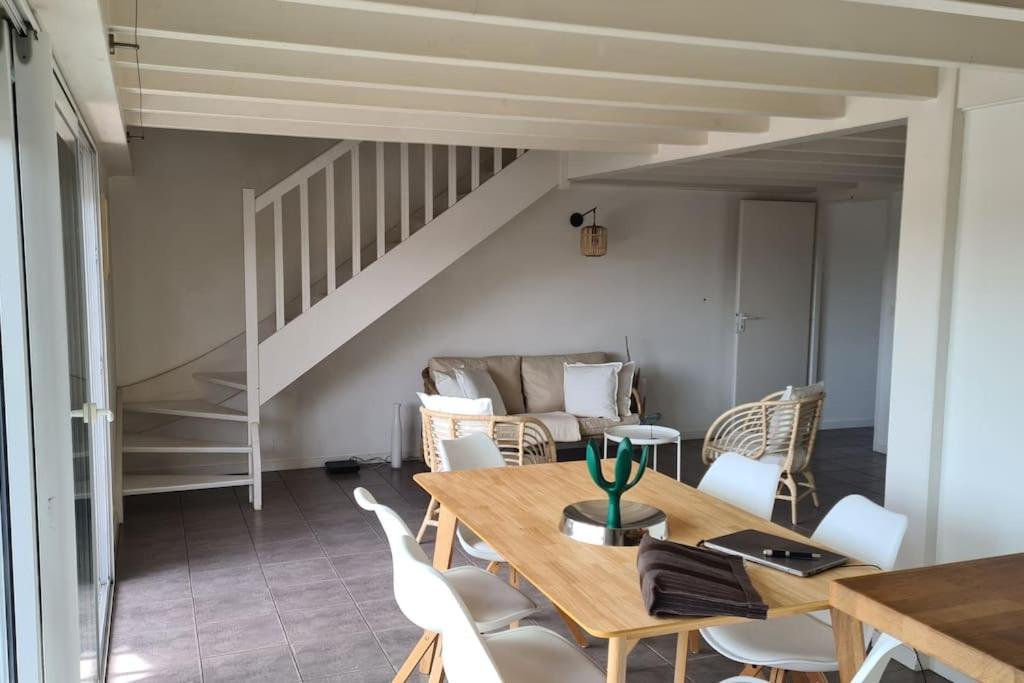 a dining room with a wooden table and white chairs at Duplex cosy au centre du Canon, à quelques pas du Bassin in Cap-Ferret