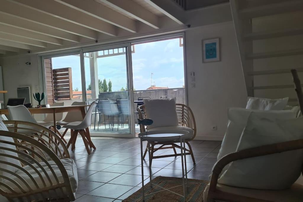 a living room with a table and chairs and a balcony at Duplex cosy au centre du Canon, à quelques pas du Bassin in Cap-Ferret