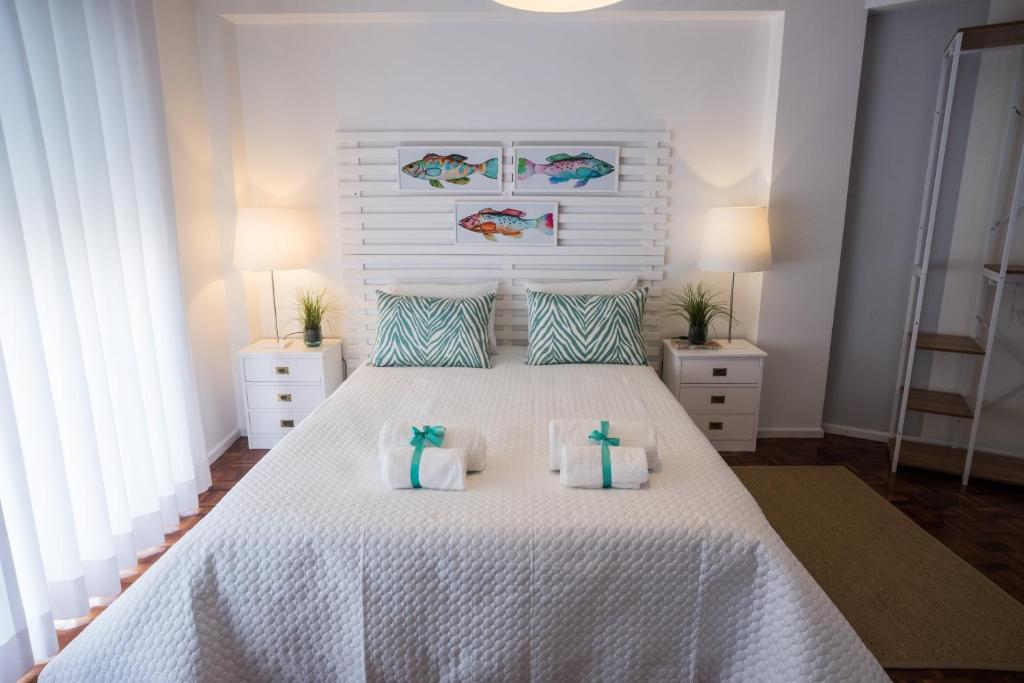 um quarto com uma cama branca e 2 almofadas em Casa "Vó Minda" - Nazaré - Alojamento Local na Nazaré