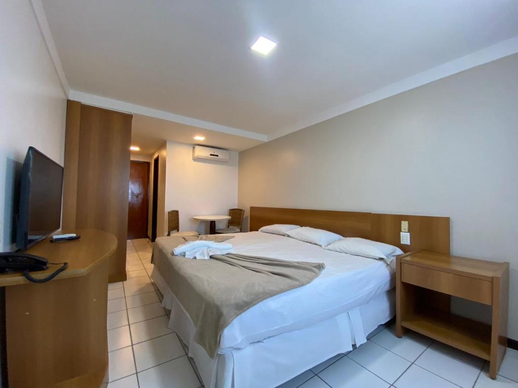 a hotel room with a bed and a television at Ponta Negra Flat ByHotéis in Natal