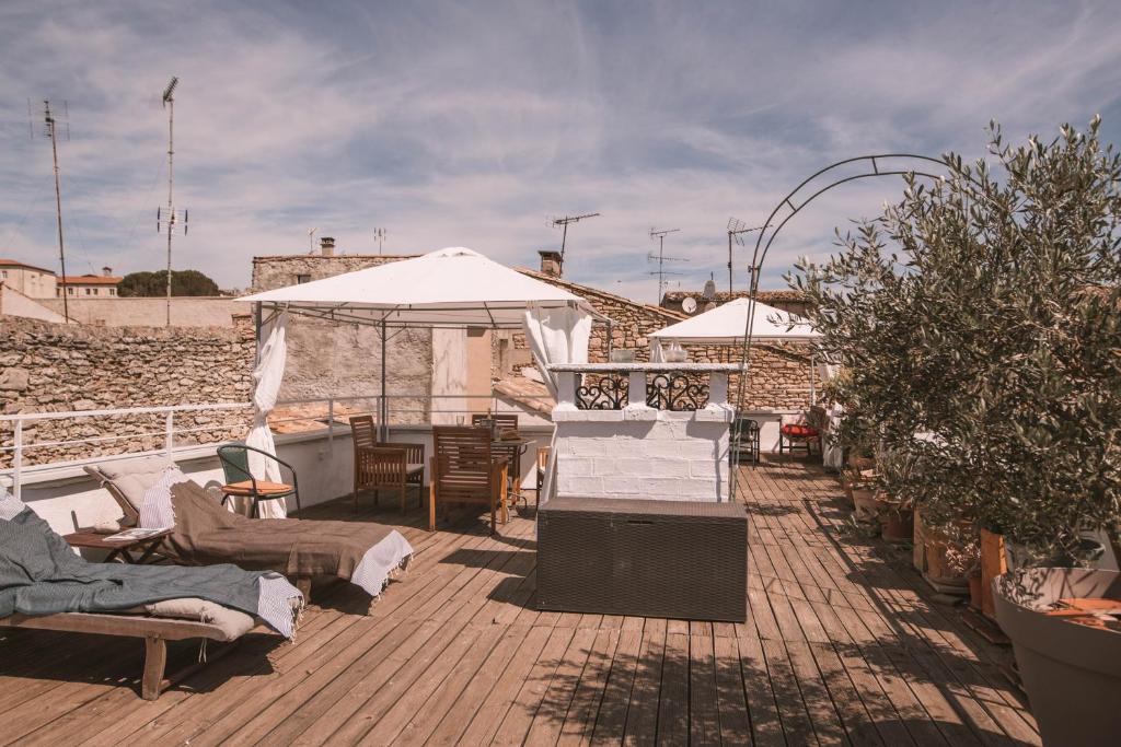 une terrasse avec des chaises, des tables et un parasol dans l'établissement Chez Pepito & Zaza hypercentre rooftop garage, à Nîmes