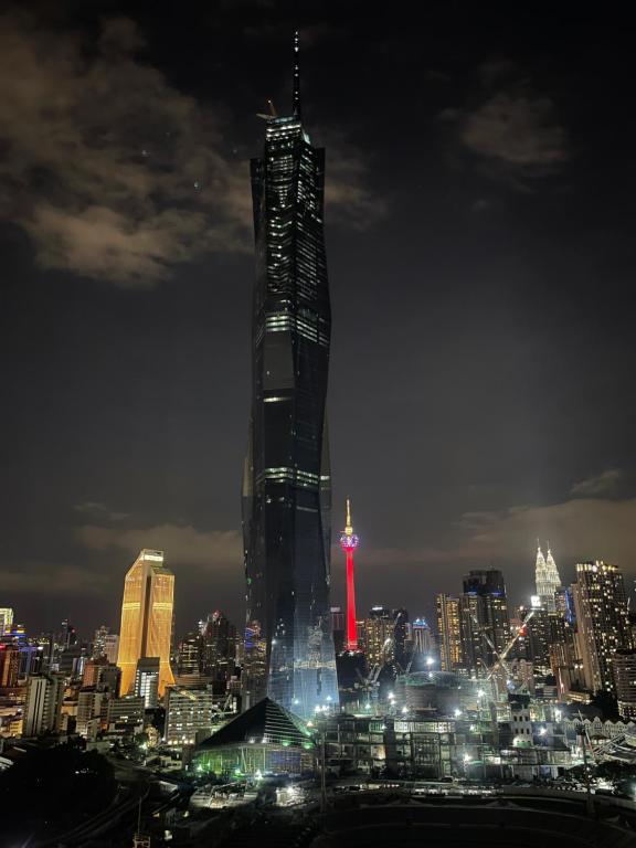 un rascacielos alto con una luz roja por la noche en Opus Residences Warisan PNB 118 View, en Kuala Lumpur