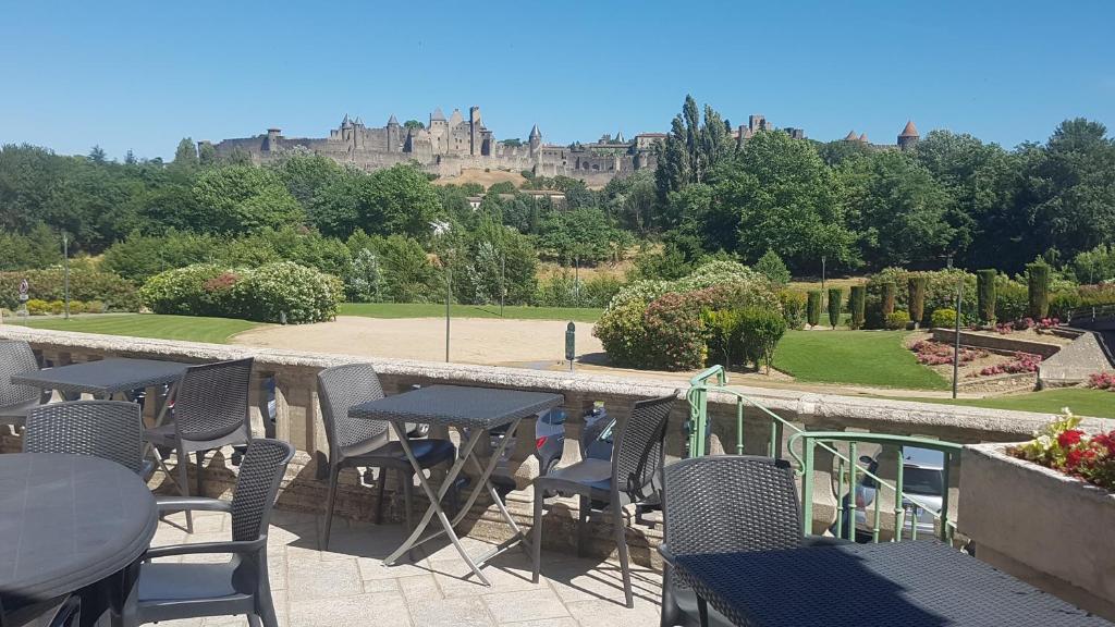 eine Terrasse mit Tischen und Stühlen und einem Schloss im Hintergrund in der Unterkunft Carcassonne Guesthouse in Carcassonne