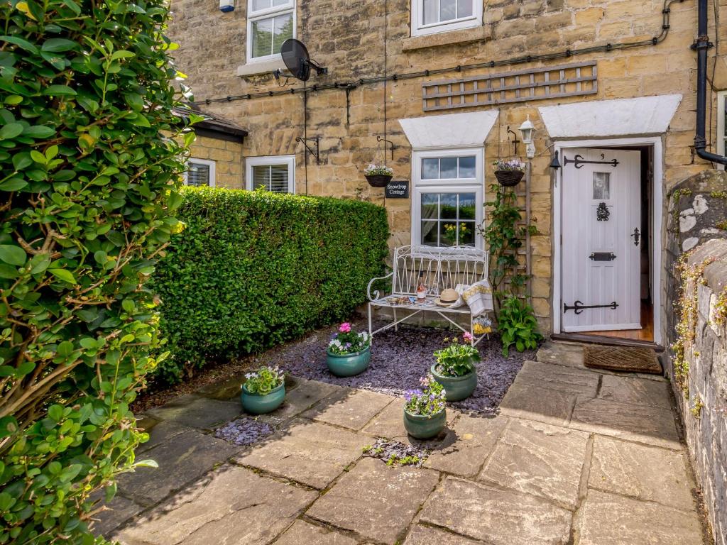 a garden with potted plants in front of a house at Snowdrop Cottage in Wetherby