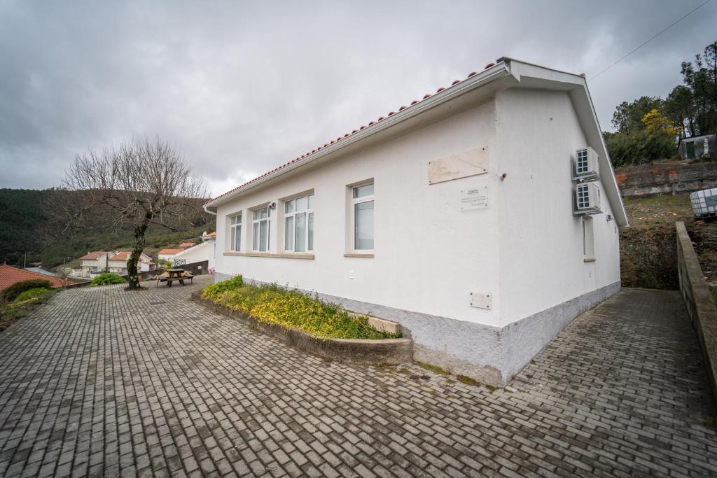 un edificio blanco sentado en un camino de ladrillo en Casa Rural "A Escola" - Meãs, Pampilhosa da Serra, en Pampilhosa da Serra