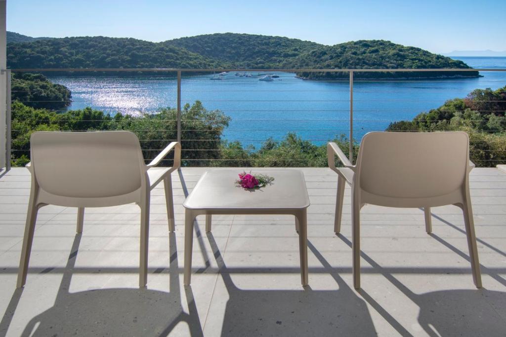 - un balcon avec 2 chaises et une table fleurie dans l'établissement Sivota Deamaris Luxury Boutique Hotel, à Sivota