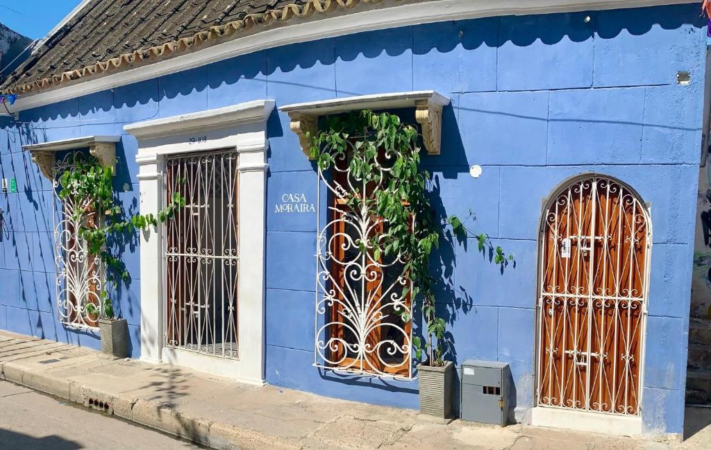 a blue building with two windows and a gate at Casa Moraira in Cartagena de Indias