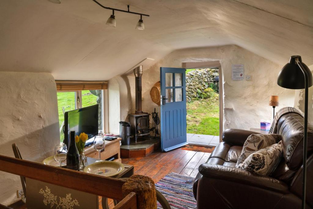 a living room with a leather couch and a television at Finest Retreats - Woodend - The Bothy in Ulpha