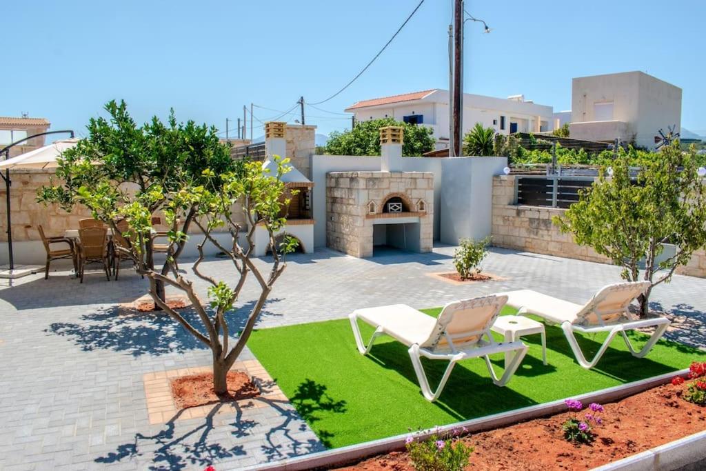 un patio con 2 sillas y chimenea en MD Residence near the beach w BBQ and private parking, en Hersonissos