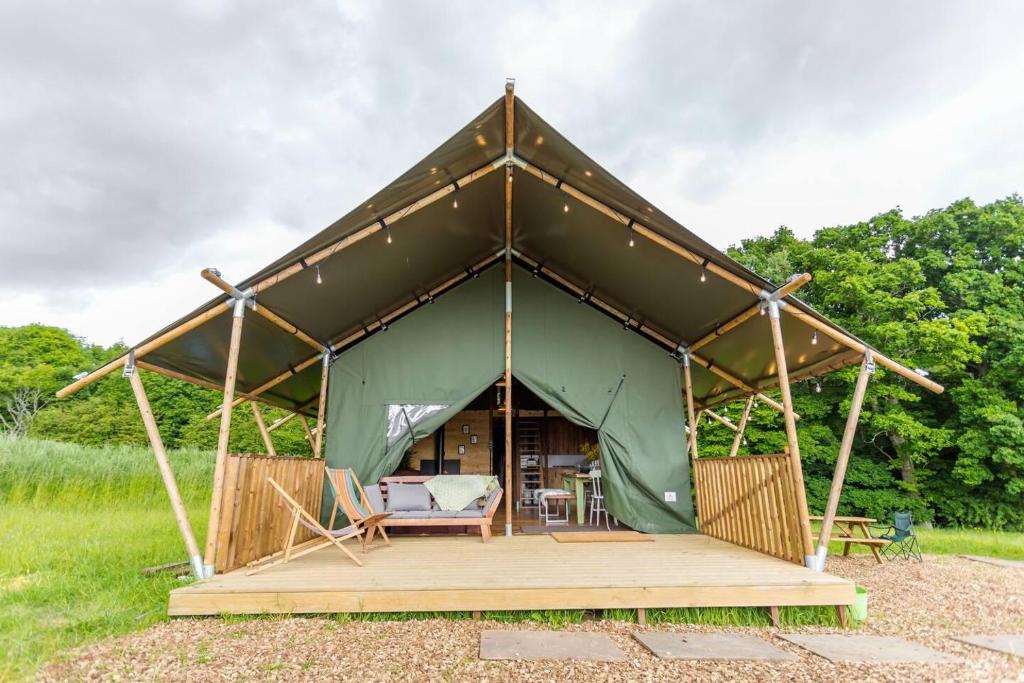une grande tente verte avec une terrasse dans un champ dans l'établissement Awe Inspiring two storey tent, à Crowhurst