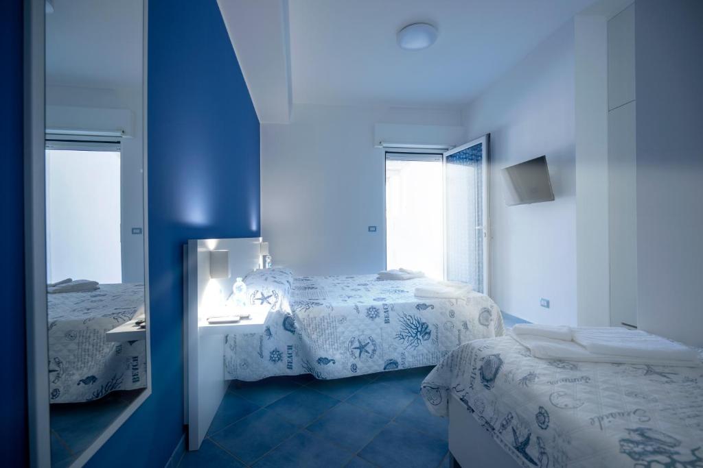 Camera blu con 2 letti e uno specchio di B&B Stella Marina a Capo dʼOrlando