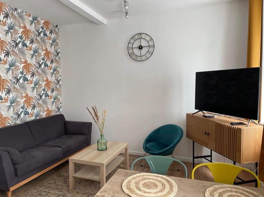 - un salon avec un canapé et une télévision dans l'établissement Les Jardins du Château, à Châteauroux