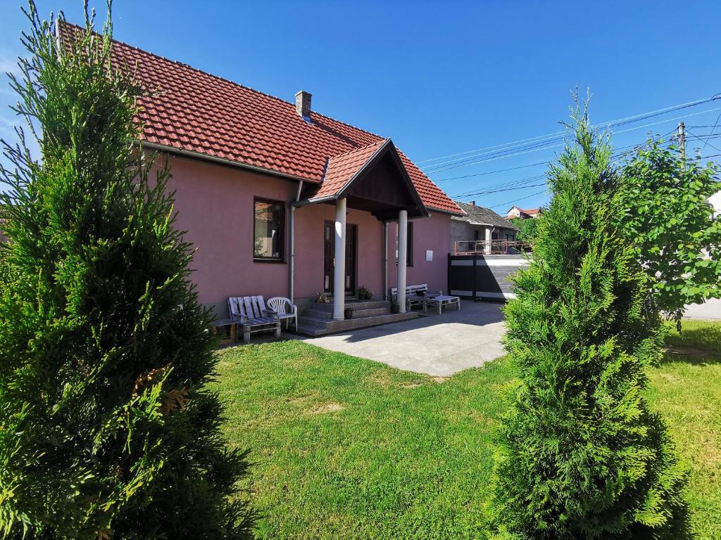 a pink house with a bench in a yard at Apartmani La Grande Motte in Vrdnik