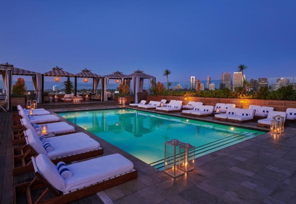 une piscine avec des chaises longues et un hôtel dans l'établissement SIXTY Beverly Hills, à Los Angeles