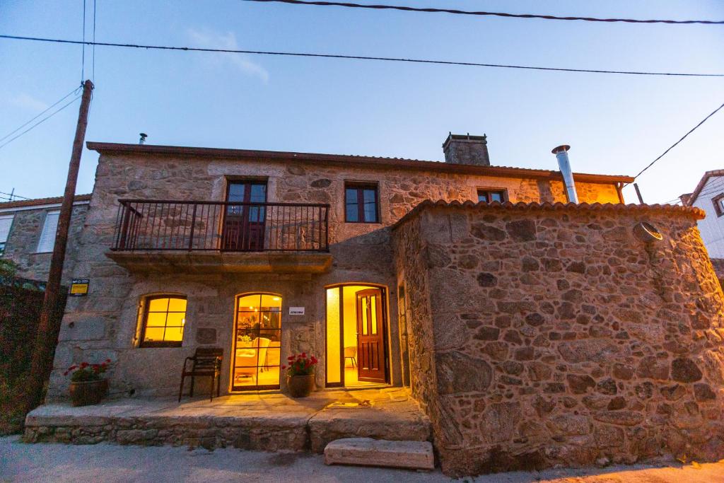 una antigua casa de piedra con un balcón en la parte superior. en Ecocasa Lema II, en Muxía