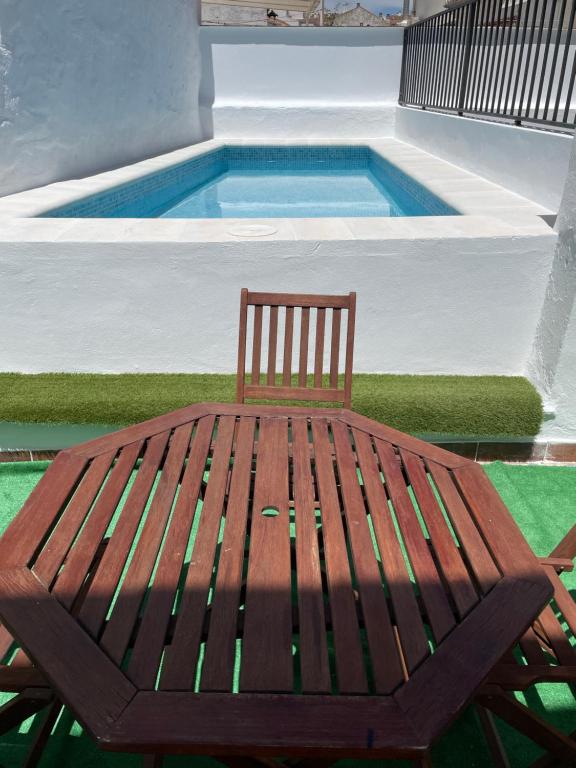 un banco de madera sentado junto a una piscina en Apartamento nuevo con piscina en el centro "Doña Paca", en Ronda