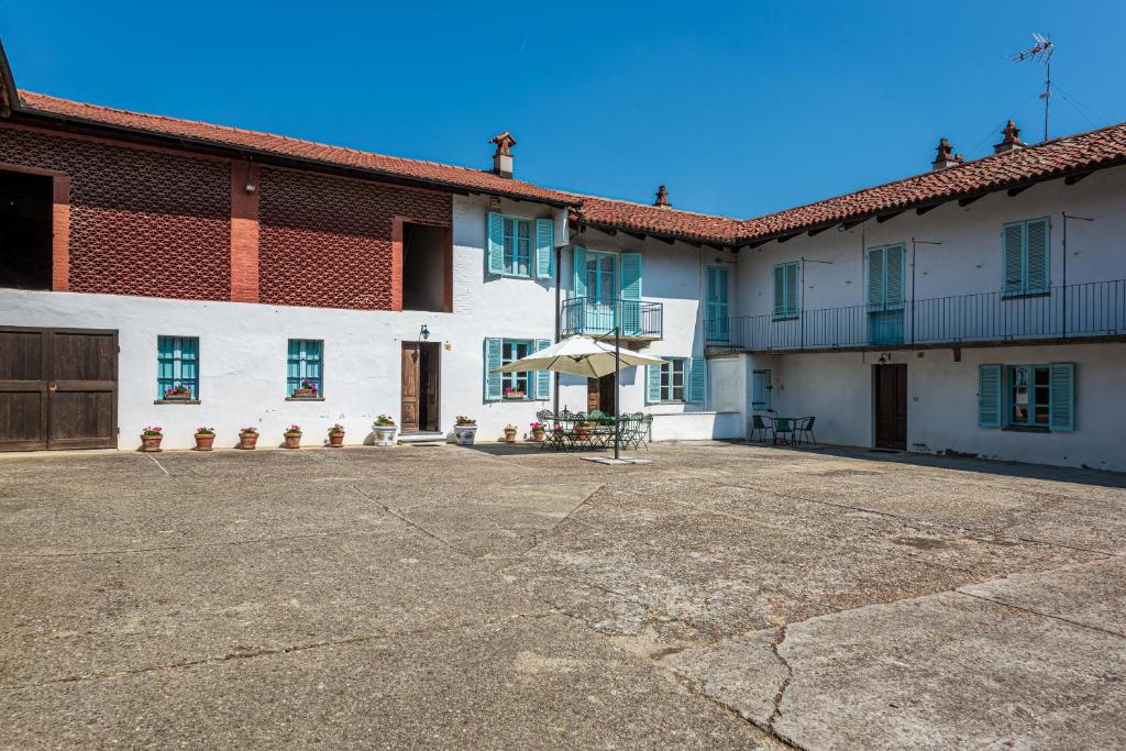a large white building with blue windows and a patio at cascina Abelloni in Diano dʼAlba