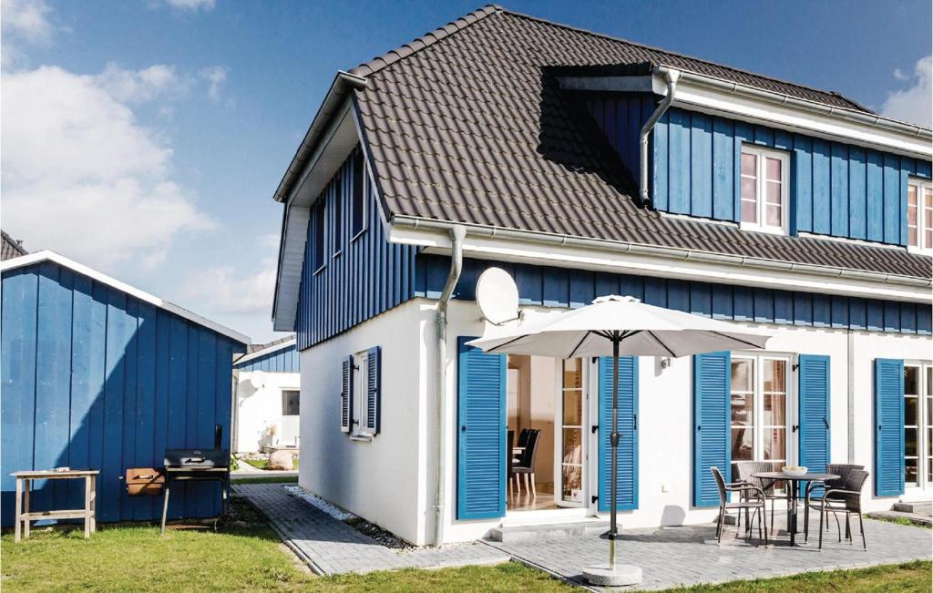 a blue and white house with a table and an umbrella at Ferienhaus 5 Altefhr in Altefähr
