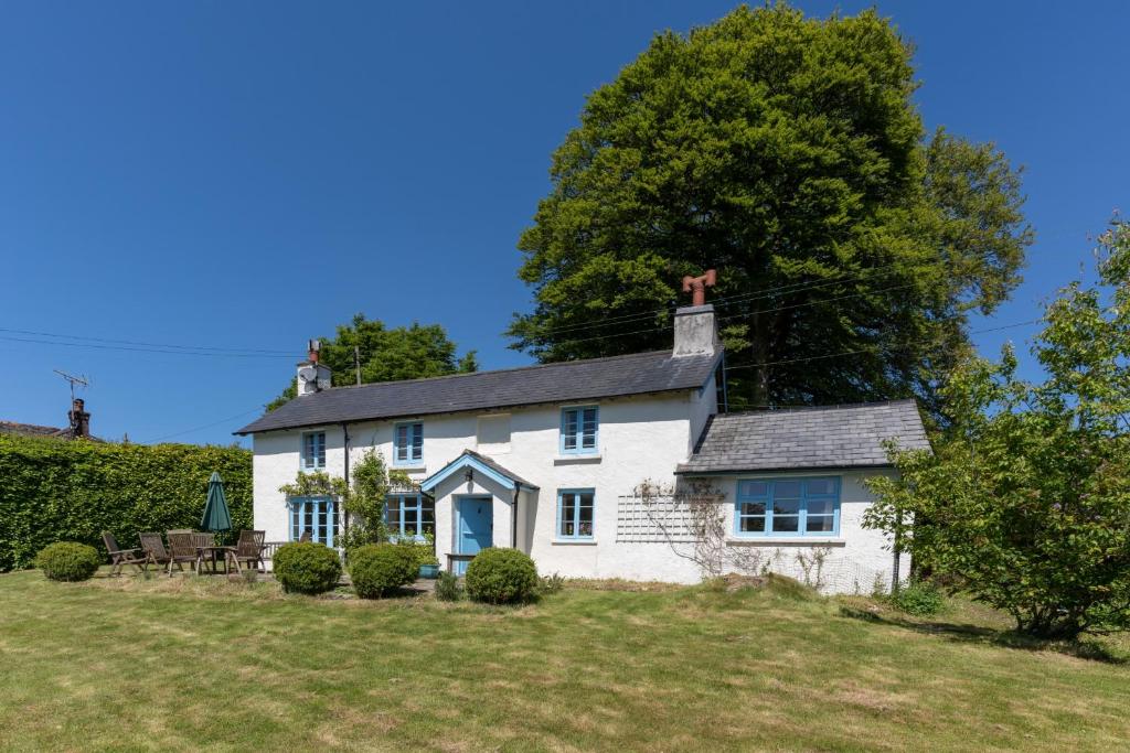 una casa blanca en una colina con un patio en Finest Retreats - Valley Cottage, en Withypool