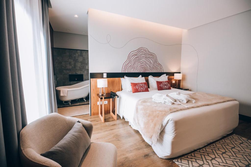 um quarto de hotel com uma cama e uma banheira em Villa Amistà Campos do Jordão em Campos de Jordão