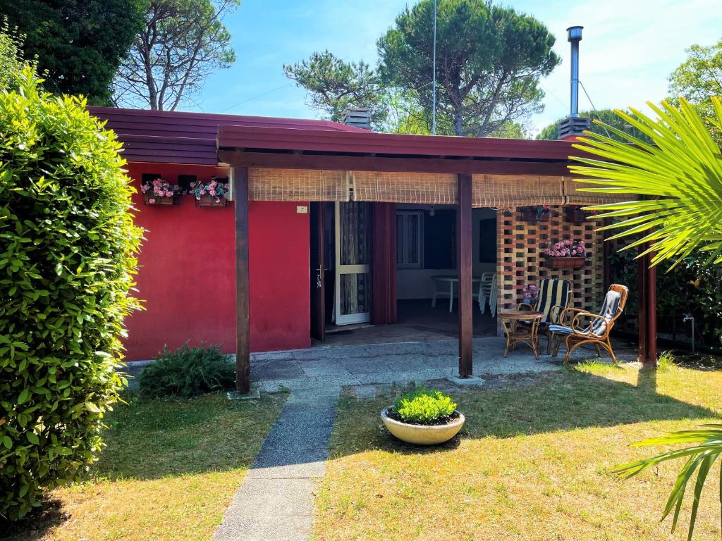 een rood huis met een tafel en stoelen in een tuin bij Villa Giulia in Bibione