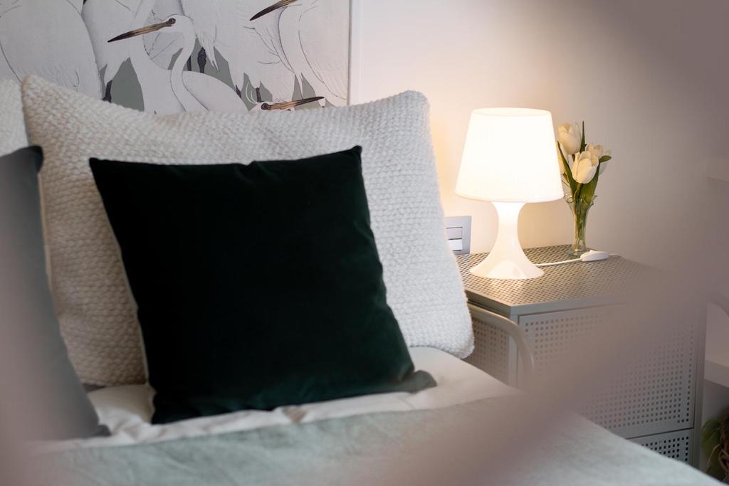 a black pillow sitting on a bed next to a lamp at Loft Ladeira Real in Baiona