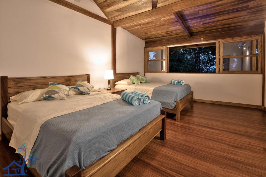 two beds in a room with wooden floors and a window at Luxury Villa Panorama Verde Pool House in Punta Uva