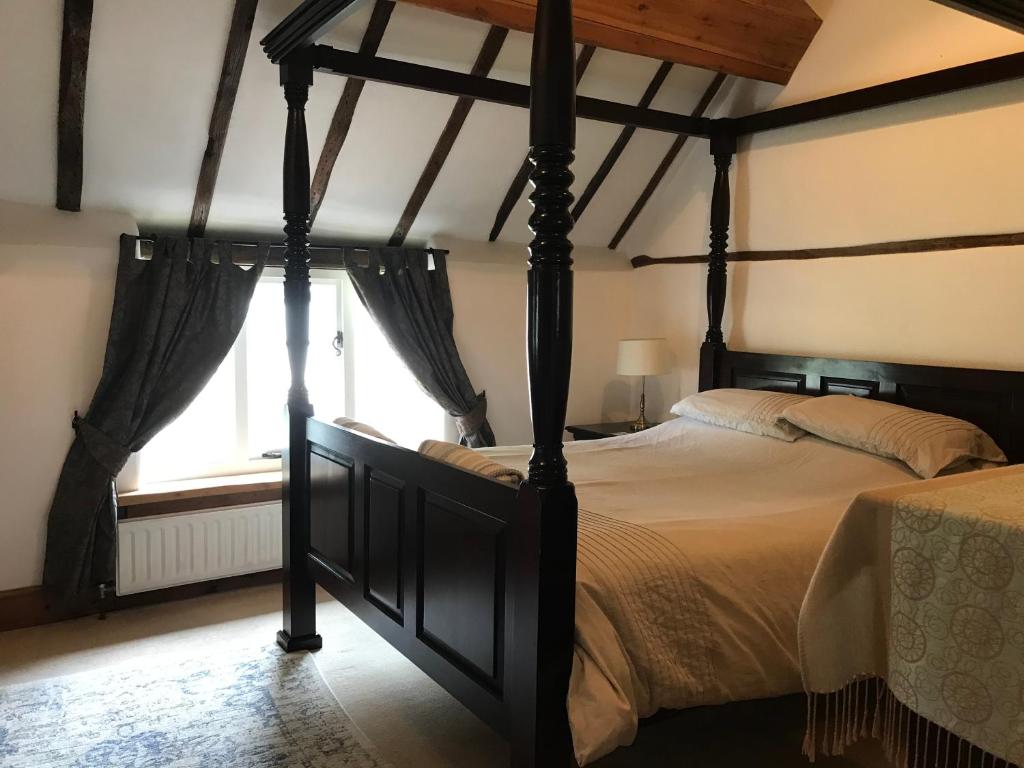 a bedroom with a four poster bed and a window at Village period cottage in Wolston
