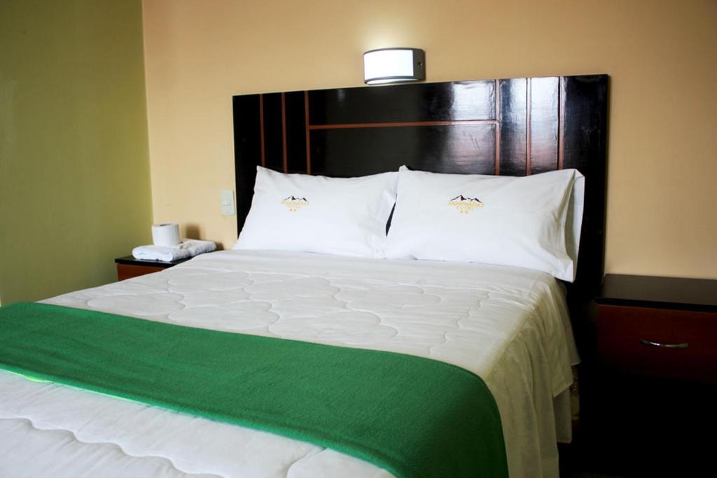 a bedroom with a large bed with a green and white comforter at Hotel Monthañas Cajamarca in Cajamarca