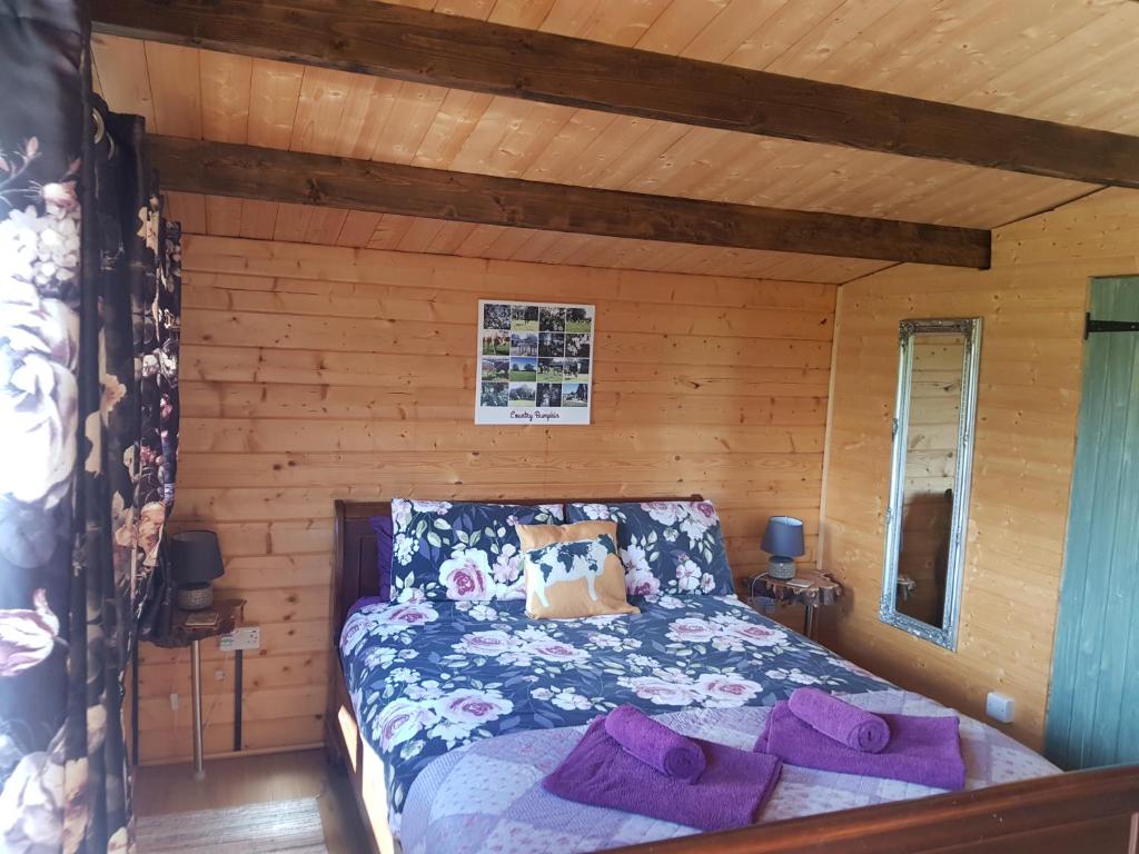 1 dormitorio con 1 cama en una cabaña de madera en Country Bumpkin - Romantic Couples stay in Oakhill Cabin en Oakhill