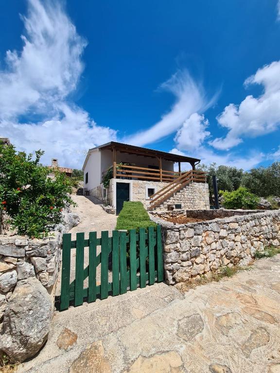 una casa con una puerta verde frente a una pared de piedra en Kuća za odmor Buba, en Murter