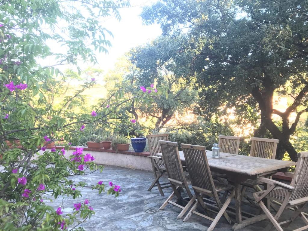 a wooden table and chairs on a patio with flowers at Appartement 3 pièces et jardin in Collioure