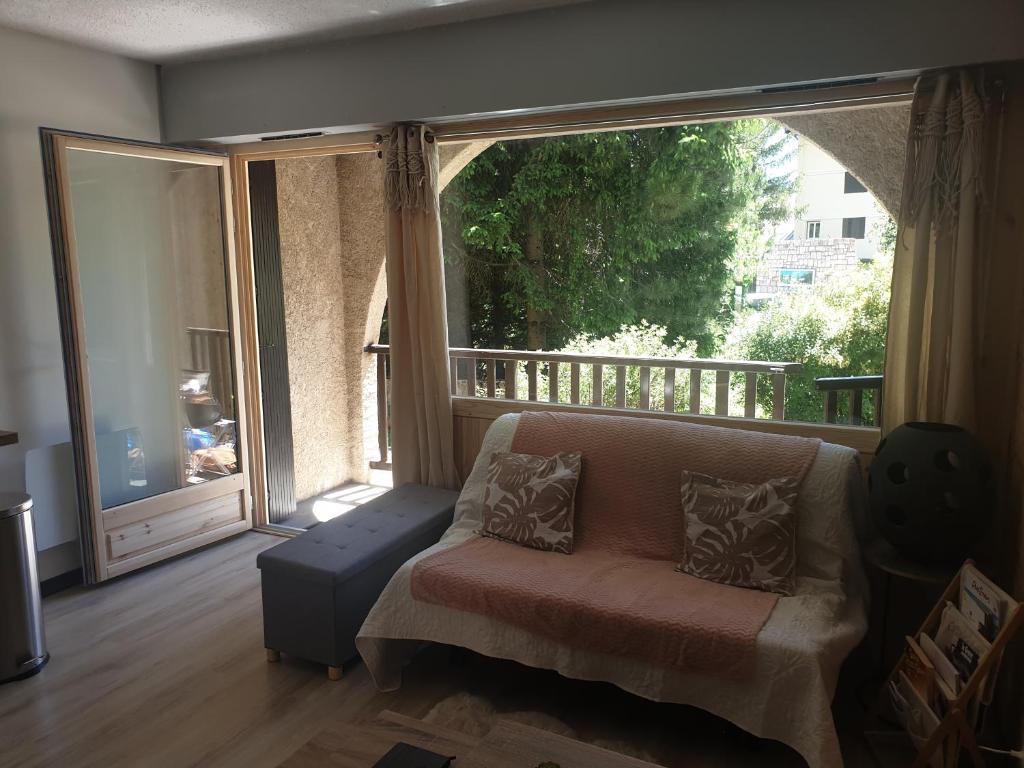 a living room with a couch and a large window at Magnifique studio, centre, parking privée,terrasse in Le Monêtier-les-Bains