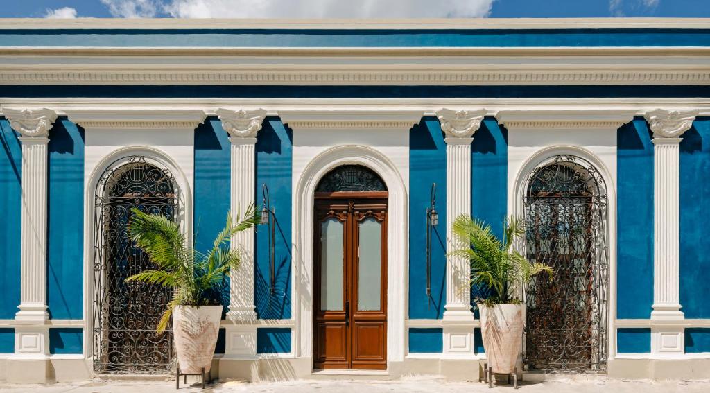een blauw gebouw met drie deuren en palmbomen voor de deur bij CIGNO HOTEL BOUTIQUE- Adults Only in Mérida