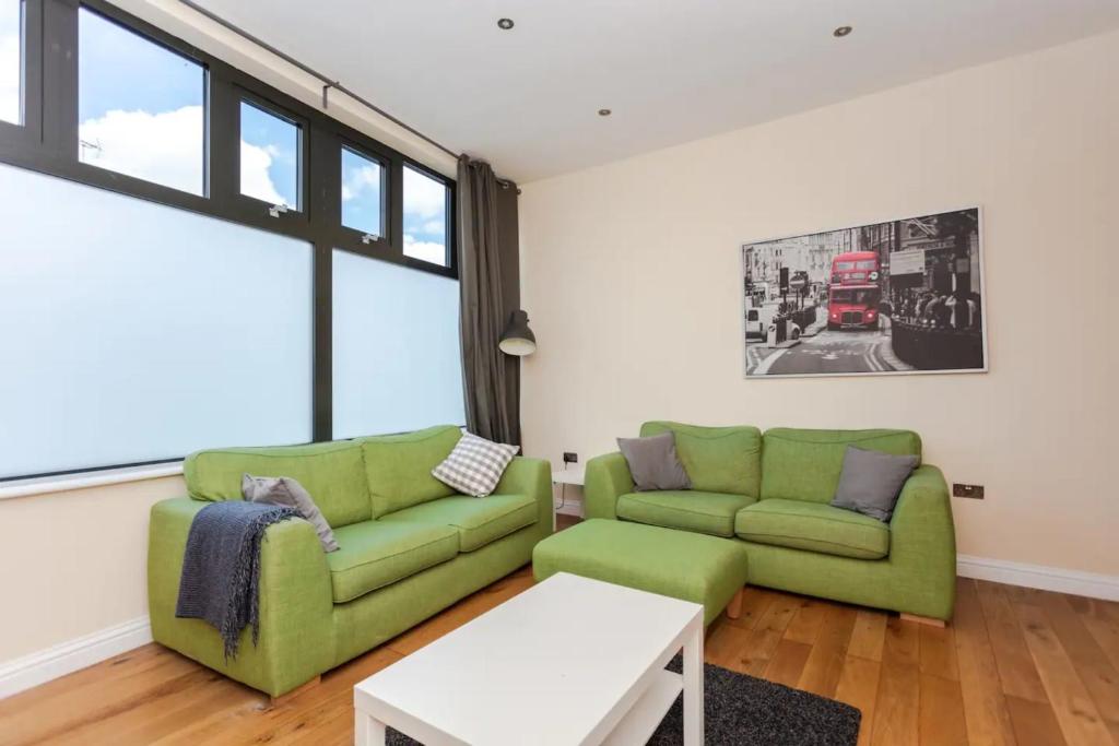 a living room with two green couches and a table at Stylish 2 Bedroom Apartment in Greenwich in London
