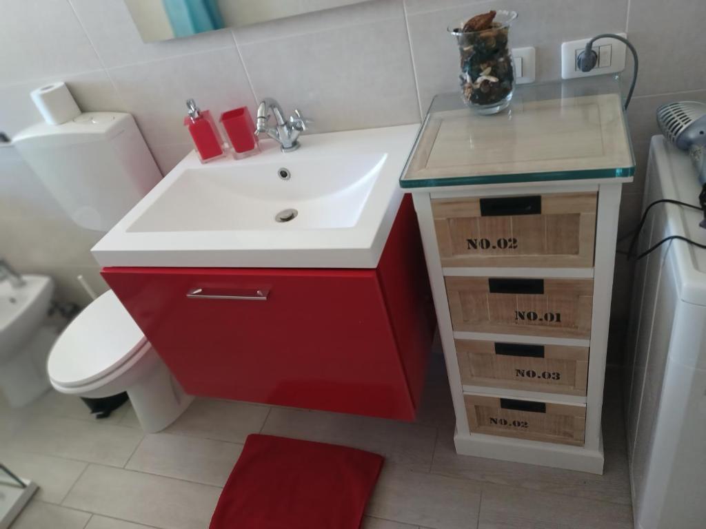 łazienka z czerwoną umywalką i toaletą w obiekcie Nikità w mieście Venaria Reale