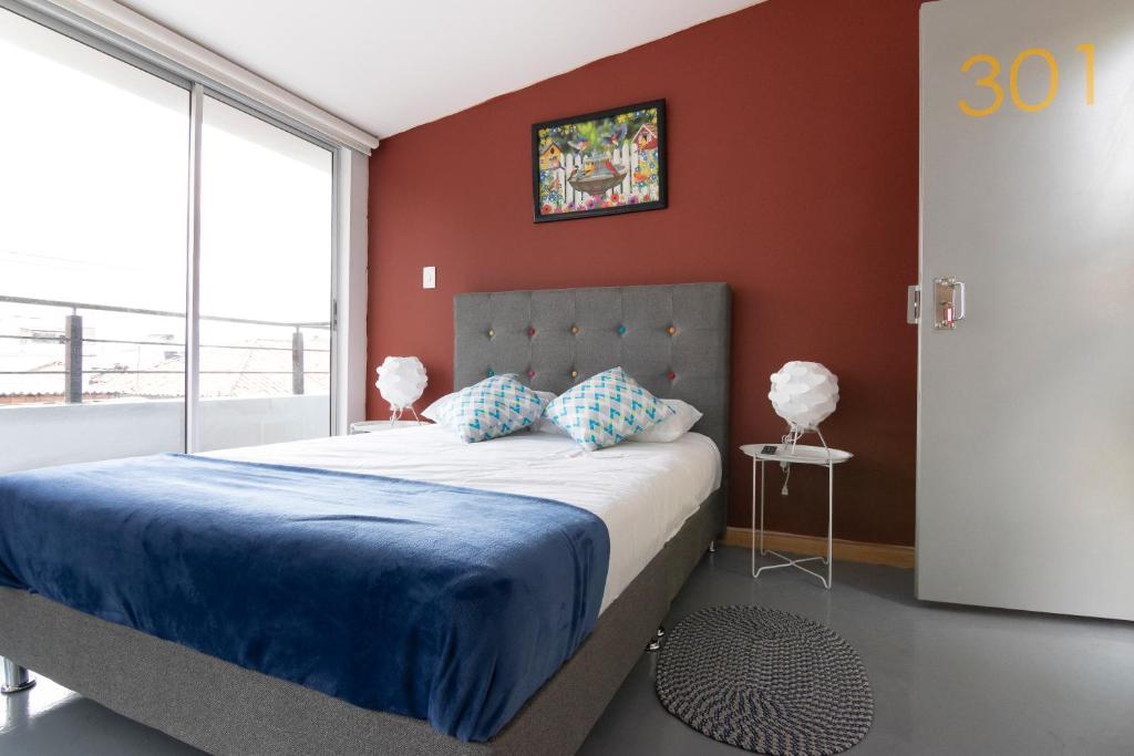 Un dormitorio con una cama con paredes rojas y una ventana en ApartaSuites Bogota Campin, en Bogotá