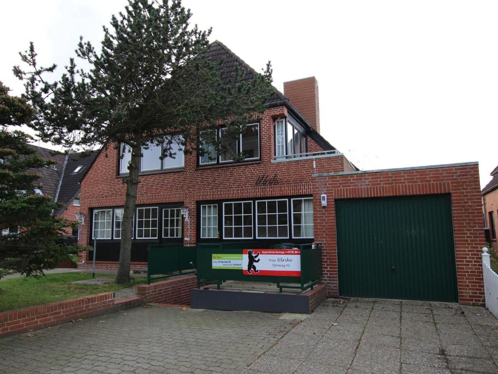 a red brick house with a green garage at Apartment in Westerland in Westerland