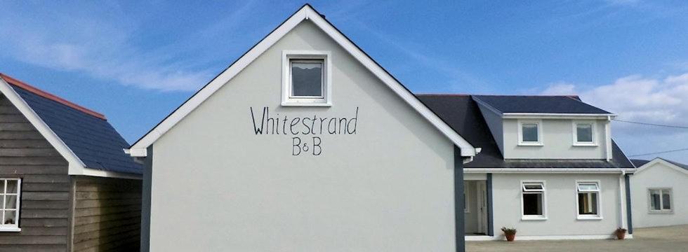 uma casa branca com escritos ao lado dela em Whitestrand B&B em Malin Head