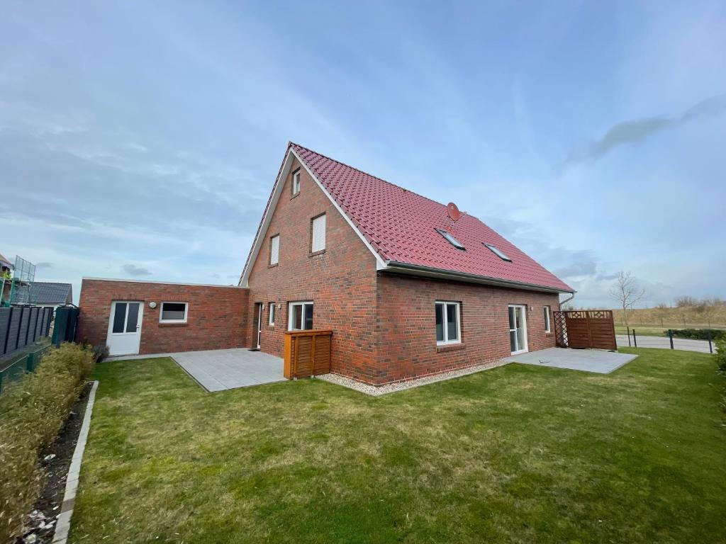 a brick house with a red roof on a yard at Am Wangermeer 38a in Wangerland